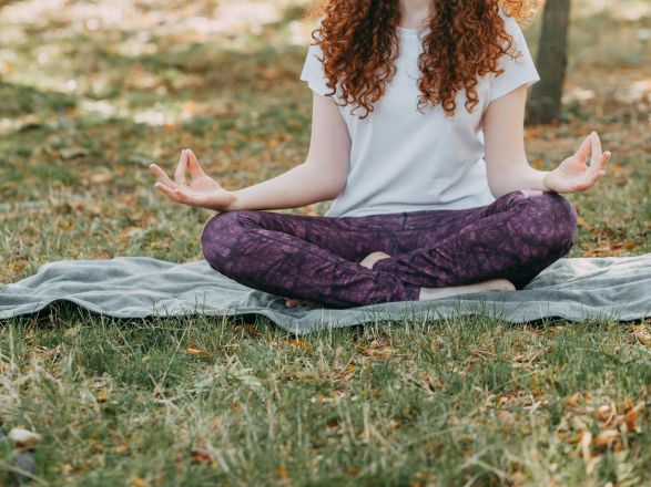 Woman meditating in a serene park during springtime, fostering relaxation and mental wellness.